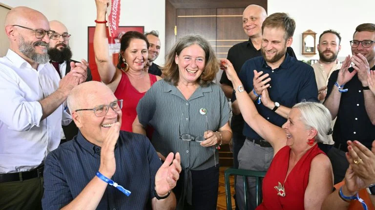 Das Bild zeigt Elke Kahr umgeben von KPÖ Funktionären. Es wird geklatscht und gefeiert.