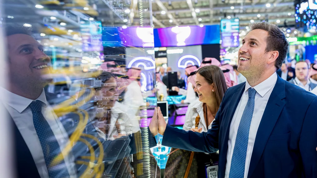 Das Bild zeigt Alexander Pröll vor einem großen Server auf einer Elektronik-Messe. Er sieht sich den Server genau an.