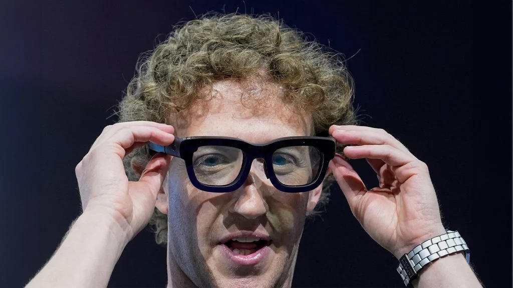 Das Bild zeigt Mark Zuckerberg, wie er sich die Meta Glasses aufsetzt.