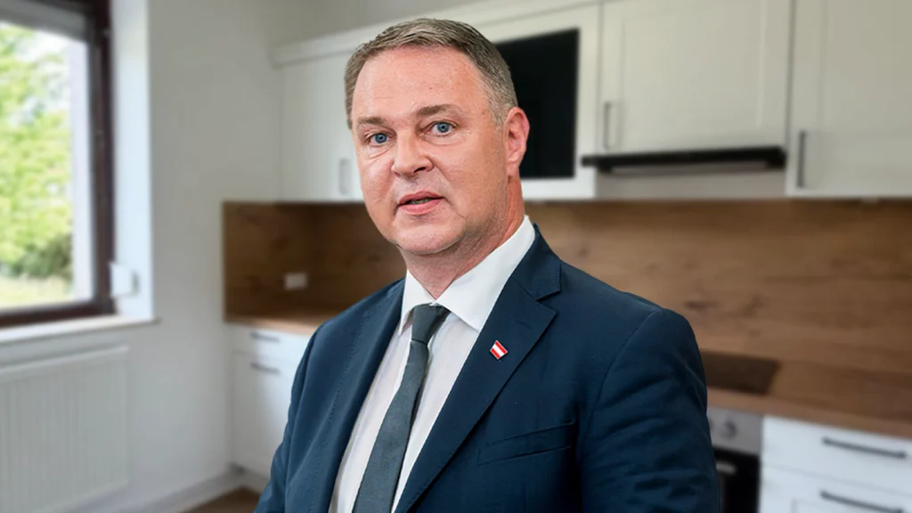 Das Bild zeigt Andreas Babler mit verwirrtem Blick in einer WG-Küche.