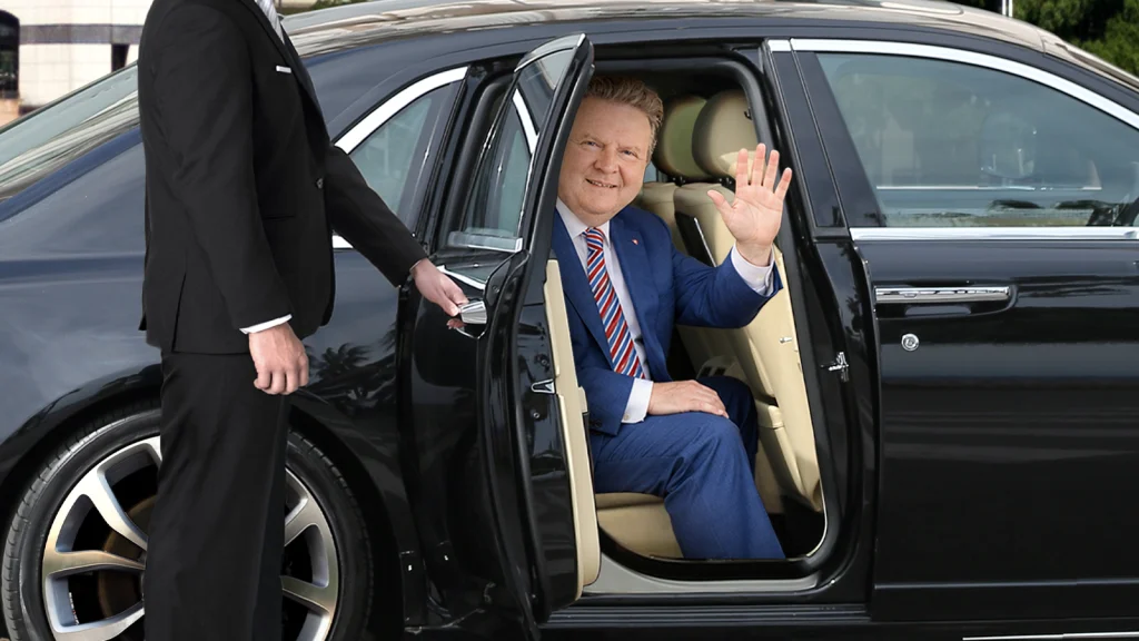 Das Bild zeigt Michael Ludwig wie er auf dem Rücksitz einer Limousine sitzt und aus dem Fenster winkt.